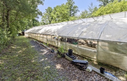 The outside of a greenhouse. Surrounded by green trees and blue sky 