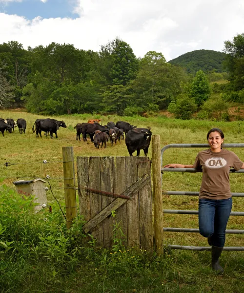 photo of farmer in front of pasture with cows