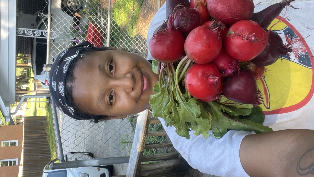 Photo of a farmer holding a bundle of beets.