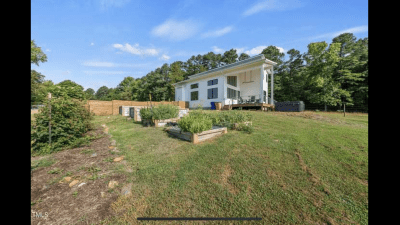 Photo of raised beds and area along the side of the house in the fenced in yard 
