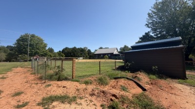 shows the large fenced yard, airbnb in distance, and barn 