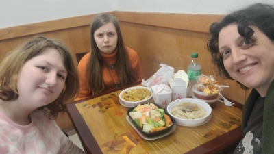 Woman and two teen girls sitting at a table about to enjoy a meal of Chinese food
