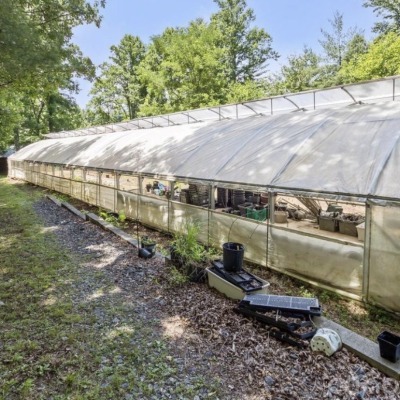 The outside of a greenhouse. Surrounded by green trees and blue sky 