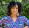 Smiling African American woman with curly hair and a shirt with echinacea blossoms