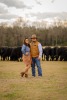 Husband and wife in pasture in front of black angus cows